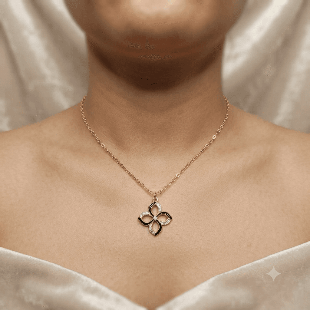 Woman wearing a black flower pendant necklace with a delicate gold-tone chain over a light outfit.