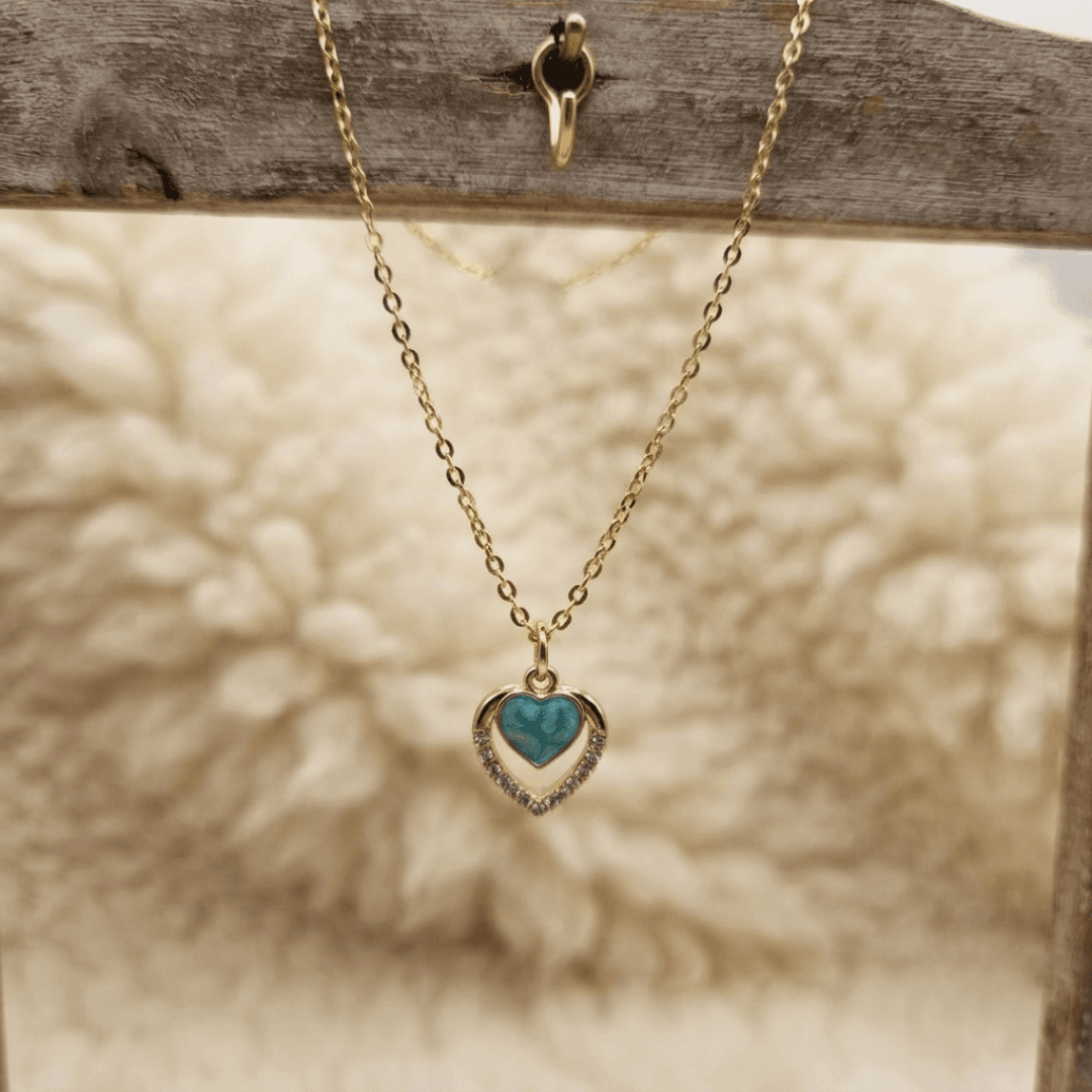 Gold-tone chain necklace with a blue heart pendant and clear sparkling-looking heart outline.