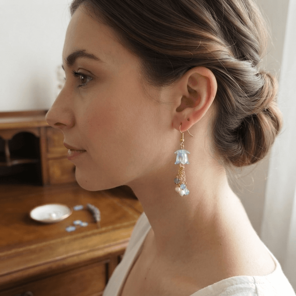 Woman wearing handmade aqua blue floral dangle earrings with translucent flower beads, gold-tone chain tassels and blue-white bead accents.
