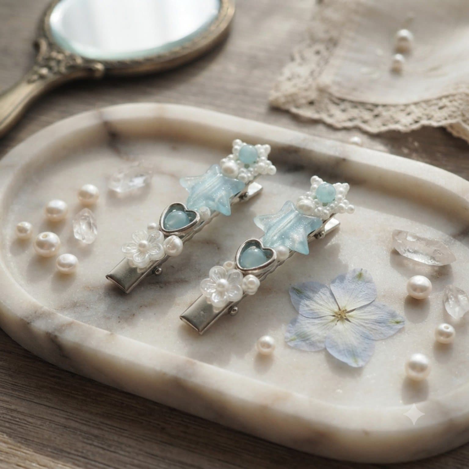 Pair of pastel blue and white beaded star hair clips displayed on a tray with heart, flower and clear bead details.