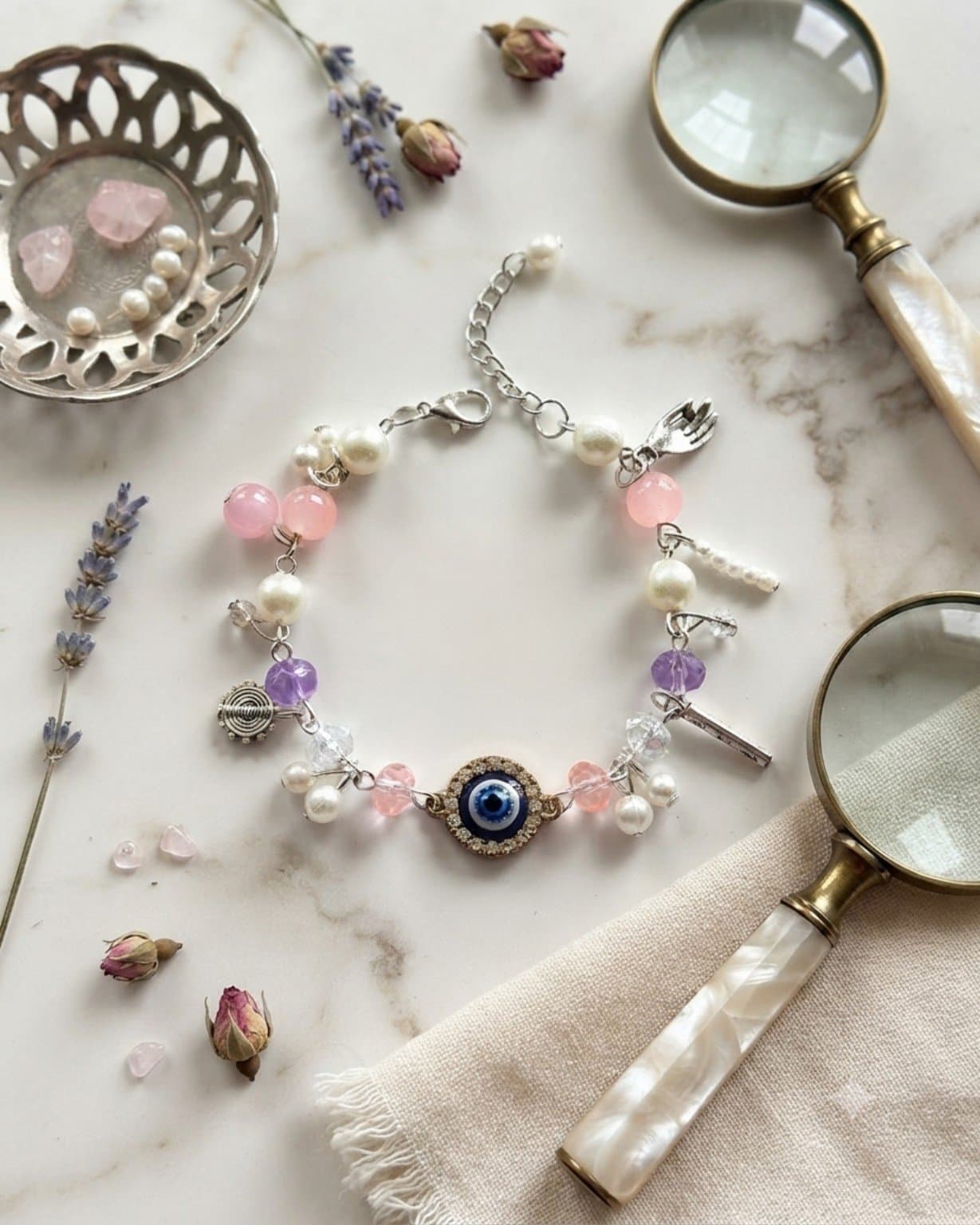 Handmade pink, lavender and white beaded chain bracelet with blue evil-eye-inspired centre charm and silver-tone clasp.