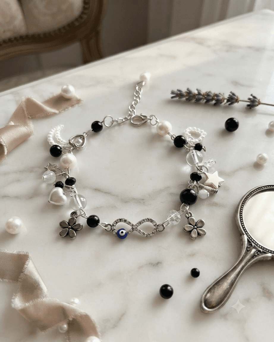 Handmade black and white beaded chain bracelet with infinity centre, blue evil-eye-inspired bead, flowers, heart and star charms.