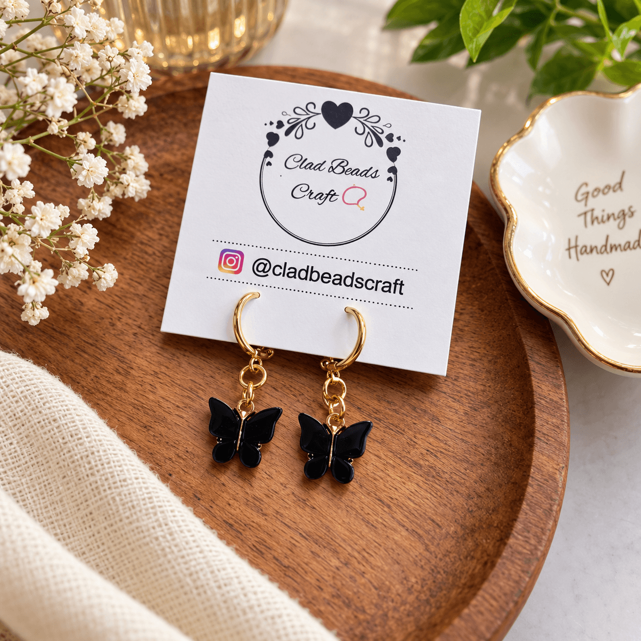 Pair of handmade black butterfly hoop earrings displayed on a Clad Beads Craft jewellery card.