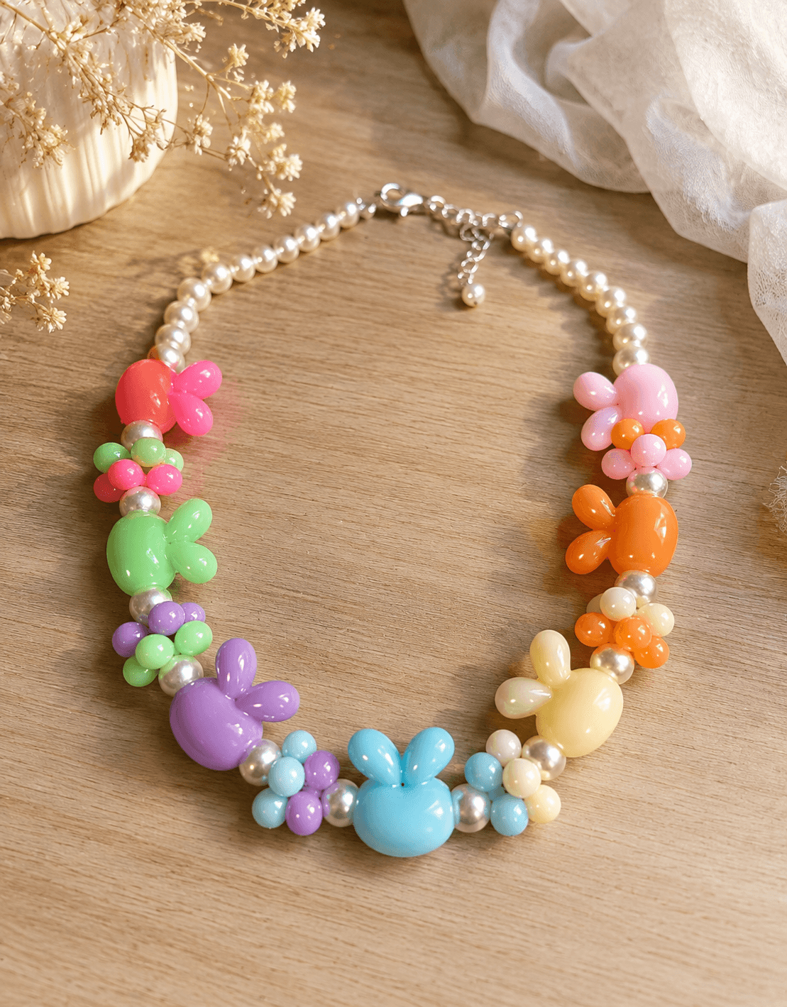 Pastel multicolor bunny and flower beaded necklace with white round beads, silver-tone spacers and an adjustable chain closure.