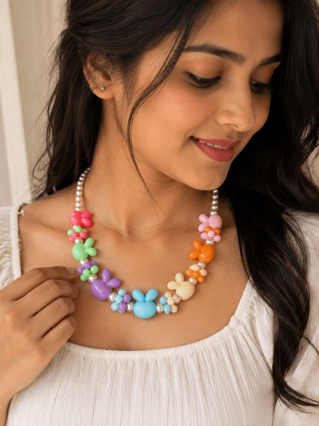 Woman wearing a handmade pastel bunny and flower beaded necklace with colourful bunny beads and white round decorative beads.