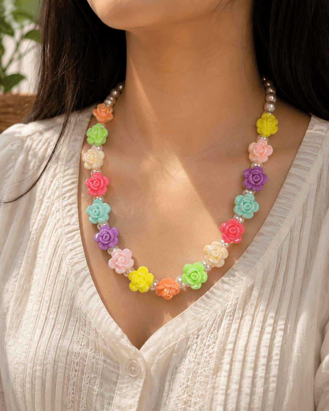Woman wearing a handmade pastel rose bead necklace with peach, mint, cream, pink, lavender, yellow and blue floral accents.