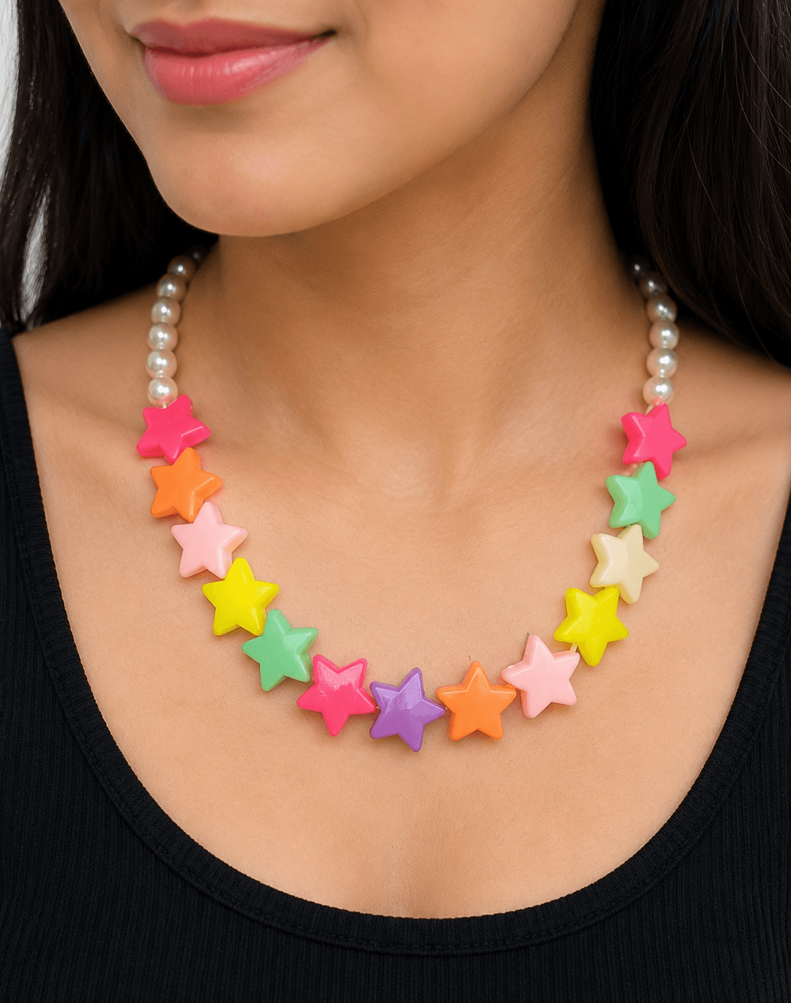 Woman wearing a handmade multicolour star bead necklace with pink, orange, yellow, green, purple and cream star accents.