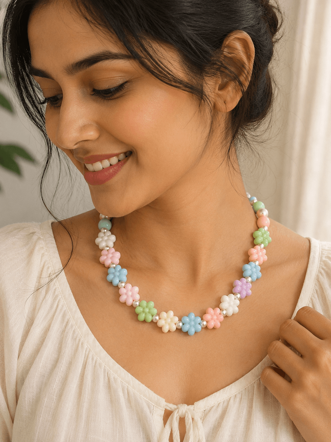 Handmade pastel flower bead necklace with pink, blue, green, peach, cream and lavender flowers worn with a white outfit.
