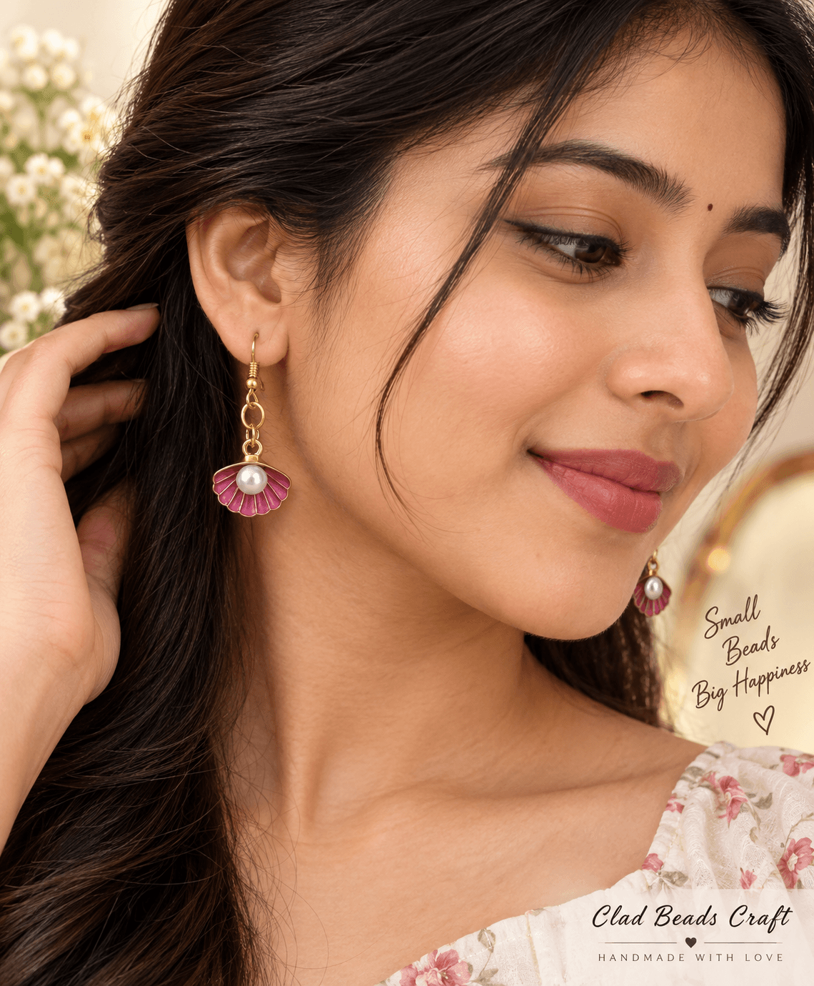 Woman wearing handmade pink floral drop earrings with pearl-look centres and gold-tone details.