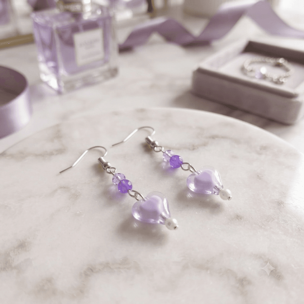 Purple heart drop earrings with purple and white beads displayed on a white marble-style surface.