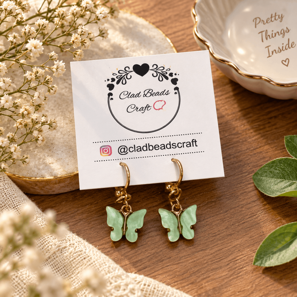 Pair of mint green butterfly dangle earrings displayed on a Clad Beads Craft jewellery card