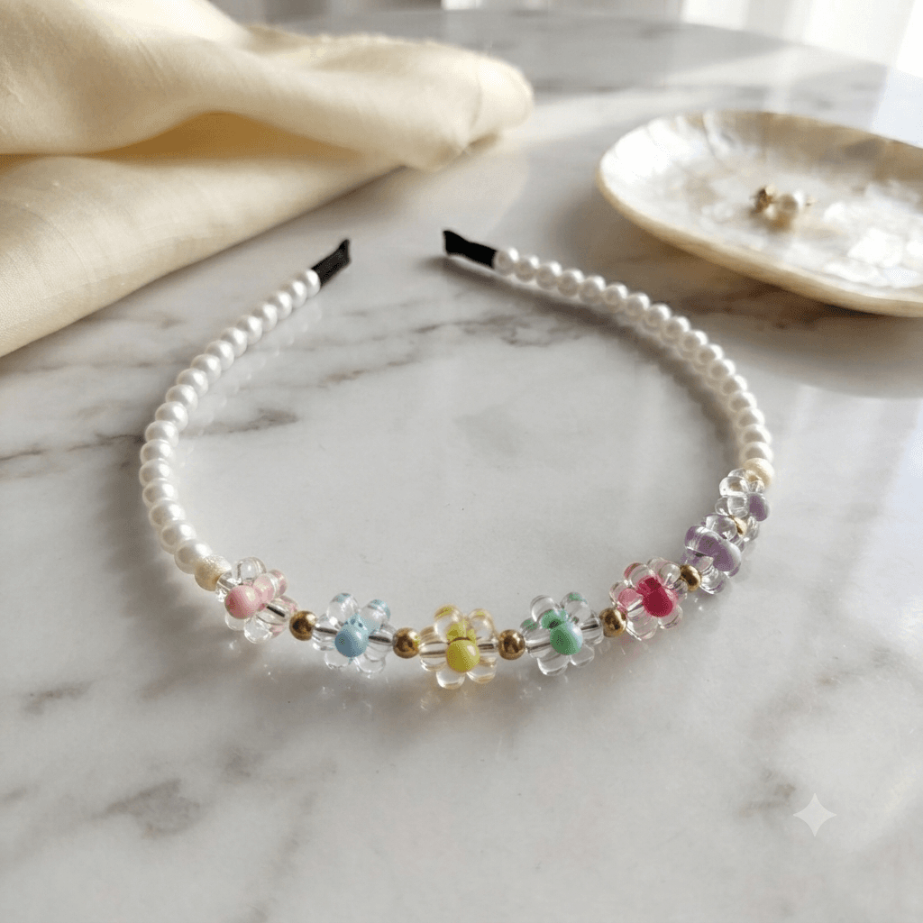 Colourful flower and pearl-look beaded headband displayed on a light marble-style surface