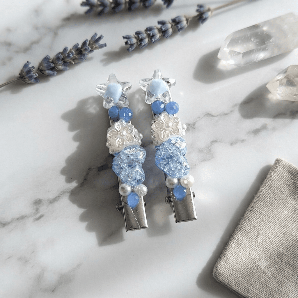 Pair of blue beaded star hair clips displayed on a white marble-style surface