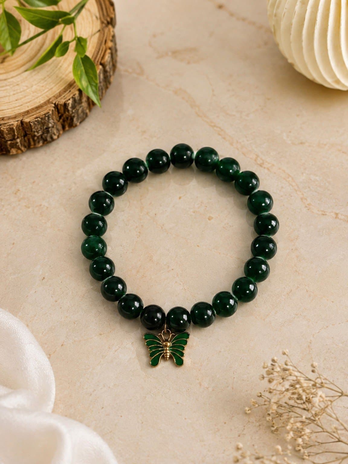Dark green glossy beaded stretch bracelet with a green butterfly charm outlined in gold-tone metal.