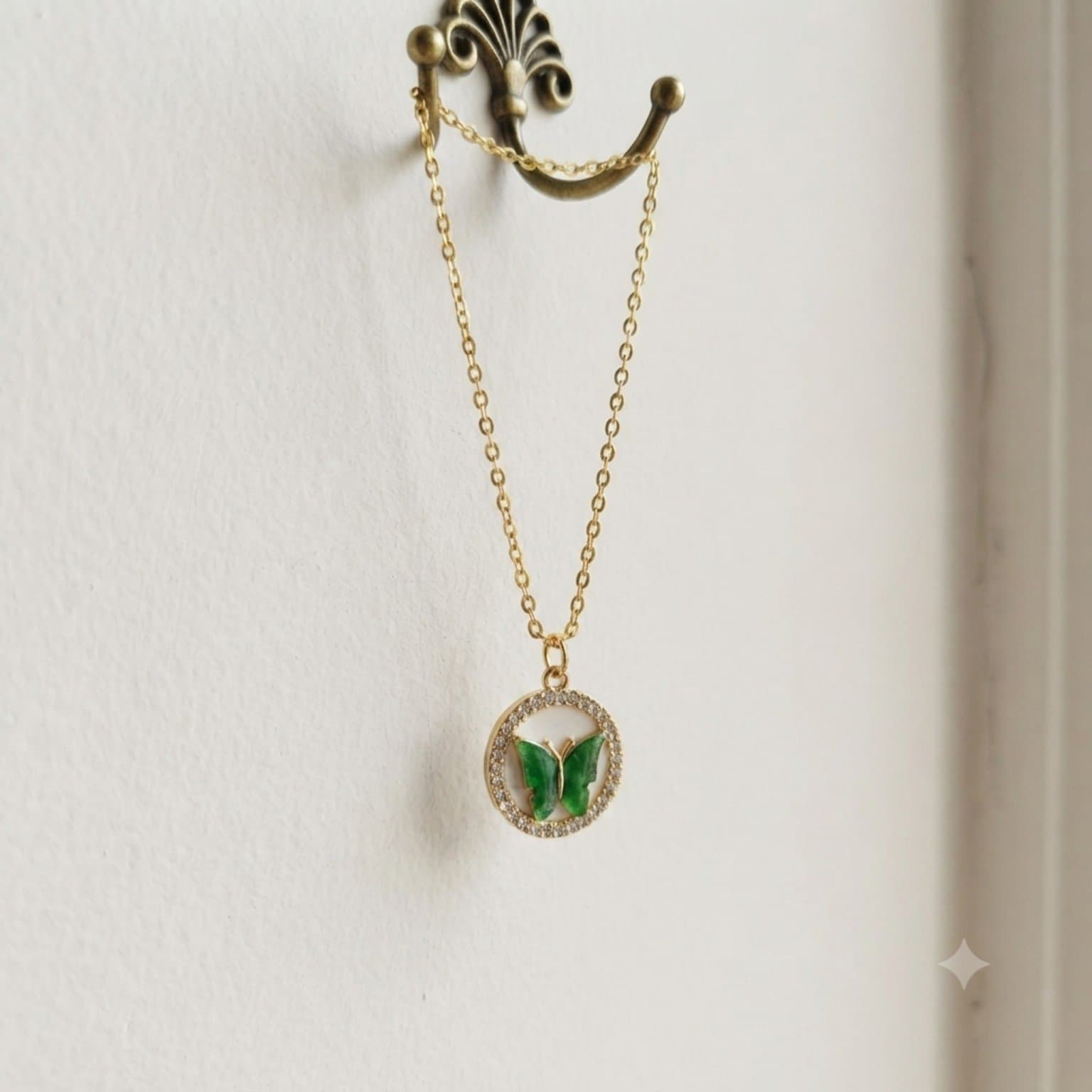 Green butterfly pendant necklace with a gold-tone chain displayed against a neutral wall..