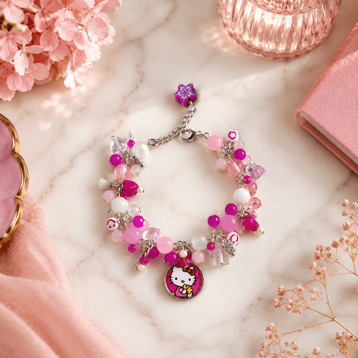 Pink handmade beaded bracelet with a Hello Kitty charm, colourful beads and silver-tone chain details displayed on a marble-style surface.
