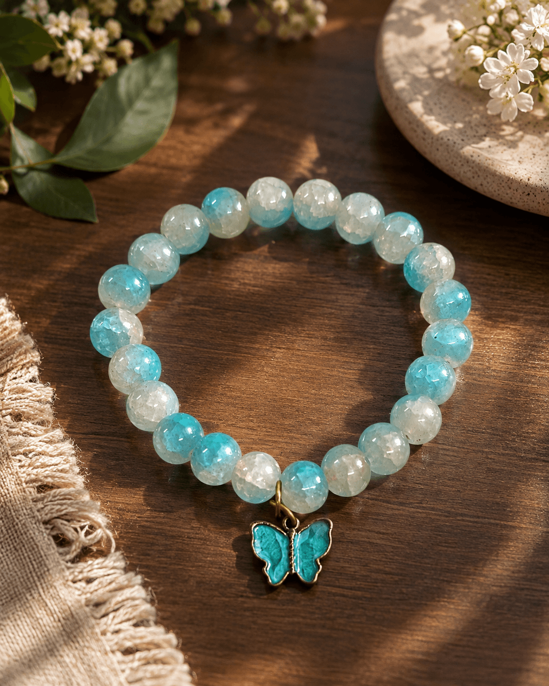 : Aqua blue and milky white crackle-finish beaded stretch bracelet with a turquoise butterfly charm.