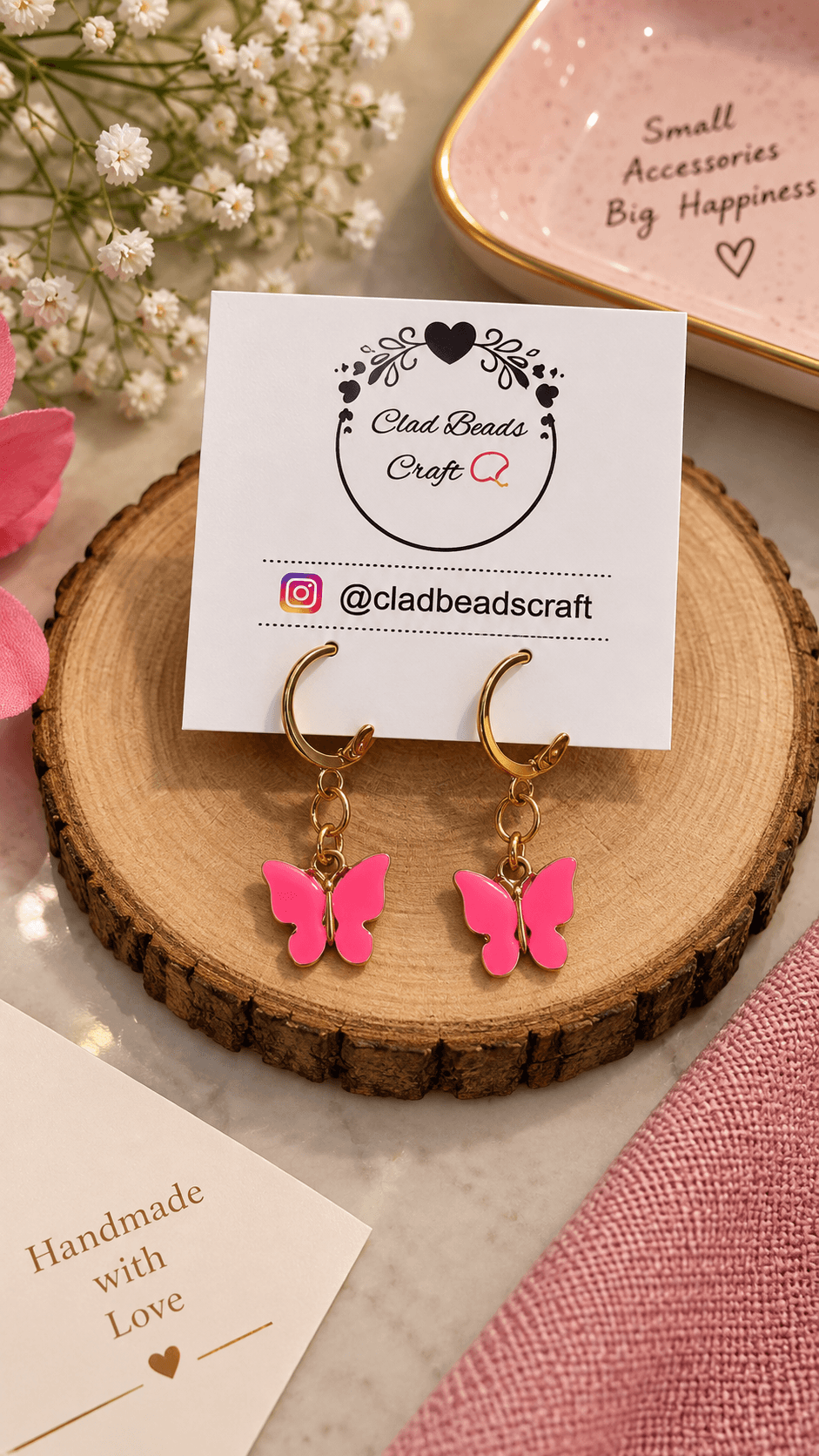 Pair of bright pink butterfly charm earrings with gold-tone alloy hoops and connecting rings displayed on a Clad Beads Craft card.