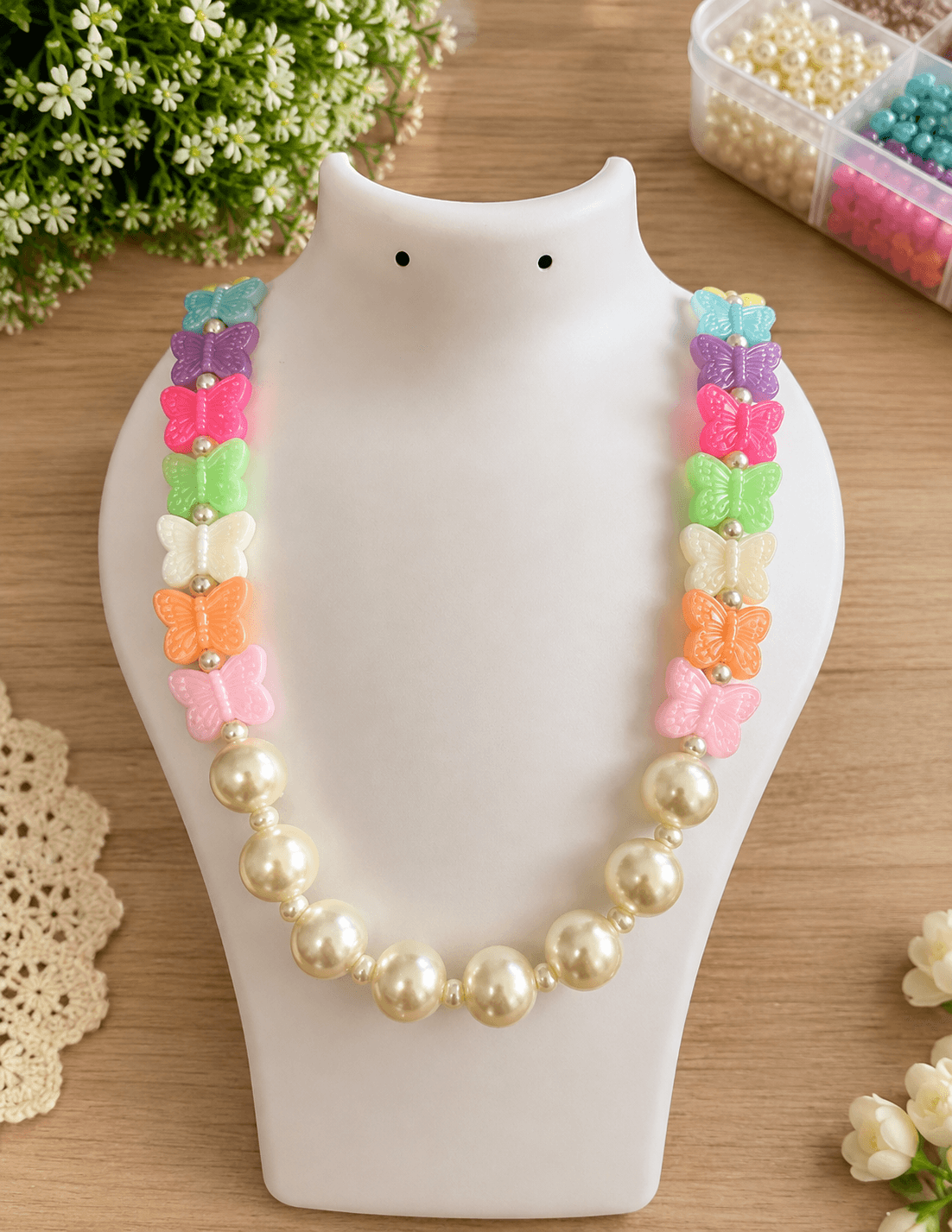 Handmade multicolor butterfly bead necklace with pastel butterfly shapes and pearl-look artificial beads on a jewellery bust.