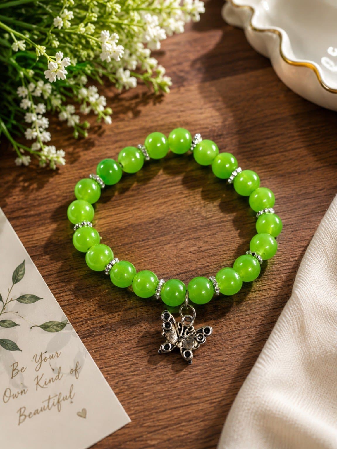 Vibrant lime green round-bead stretch bracelet with silver-tone spacer beads and a butterfly charm.