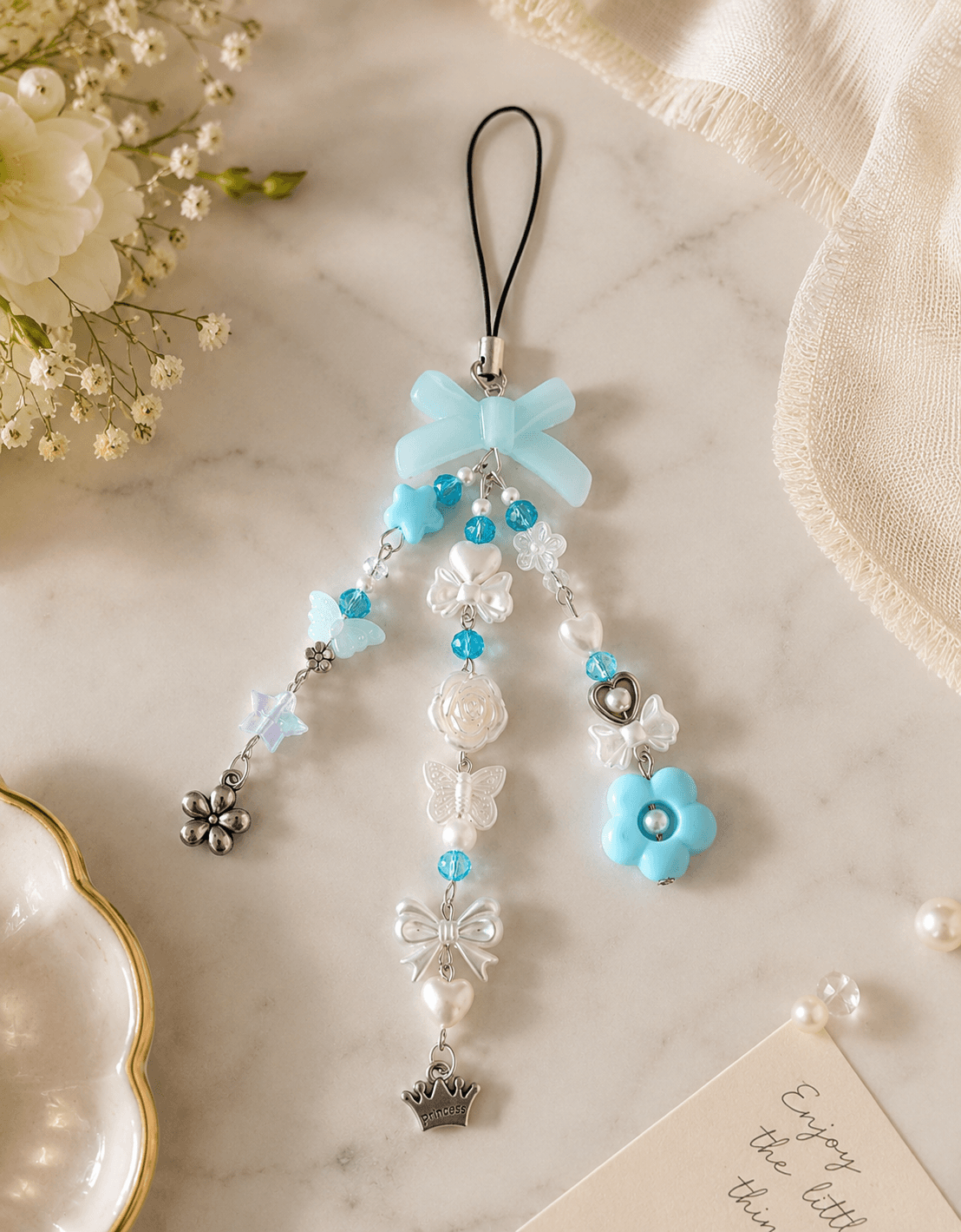 Handmade lavender and purple beaded phone charm strap displayed with butterfly, bow, flower, teddy-bear and star details.